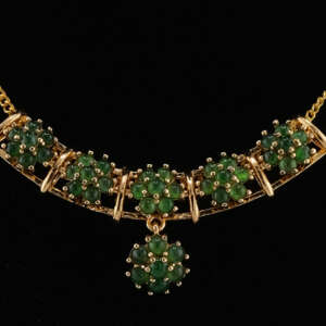 Macro close-up of natural jadeite cabochon clusters in the necklace’s center, showing detailed gold-tone prongs and the smooth translucency of each vivid green stone