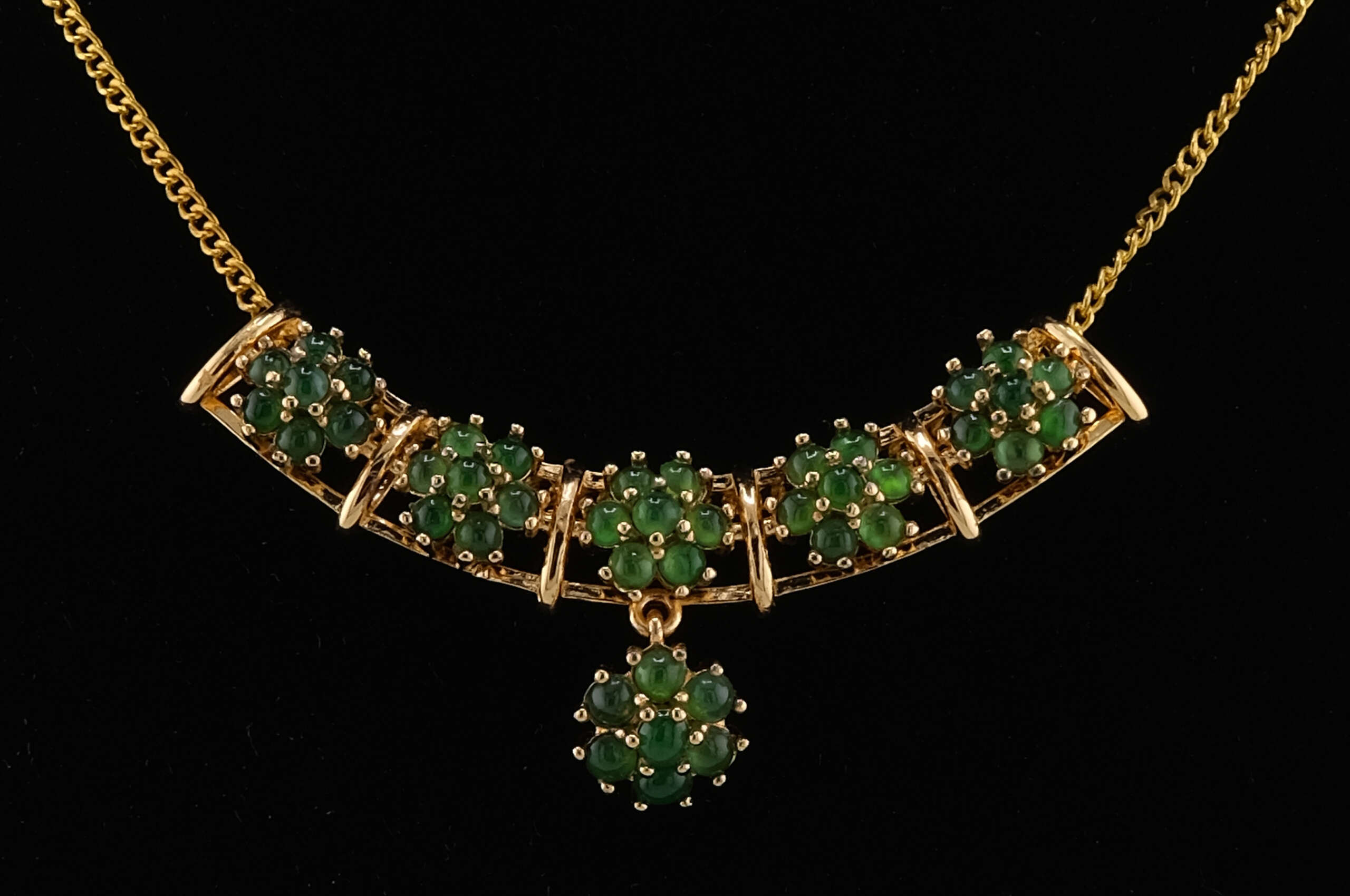 Macro close-up of natural jadeite cabochon clusters in the necklace’s center, showing detailed gold-tone prongs and the smooth translucency of each vivid green stone