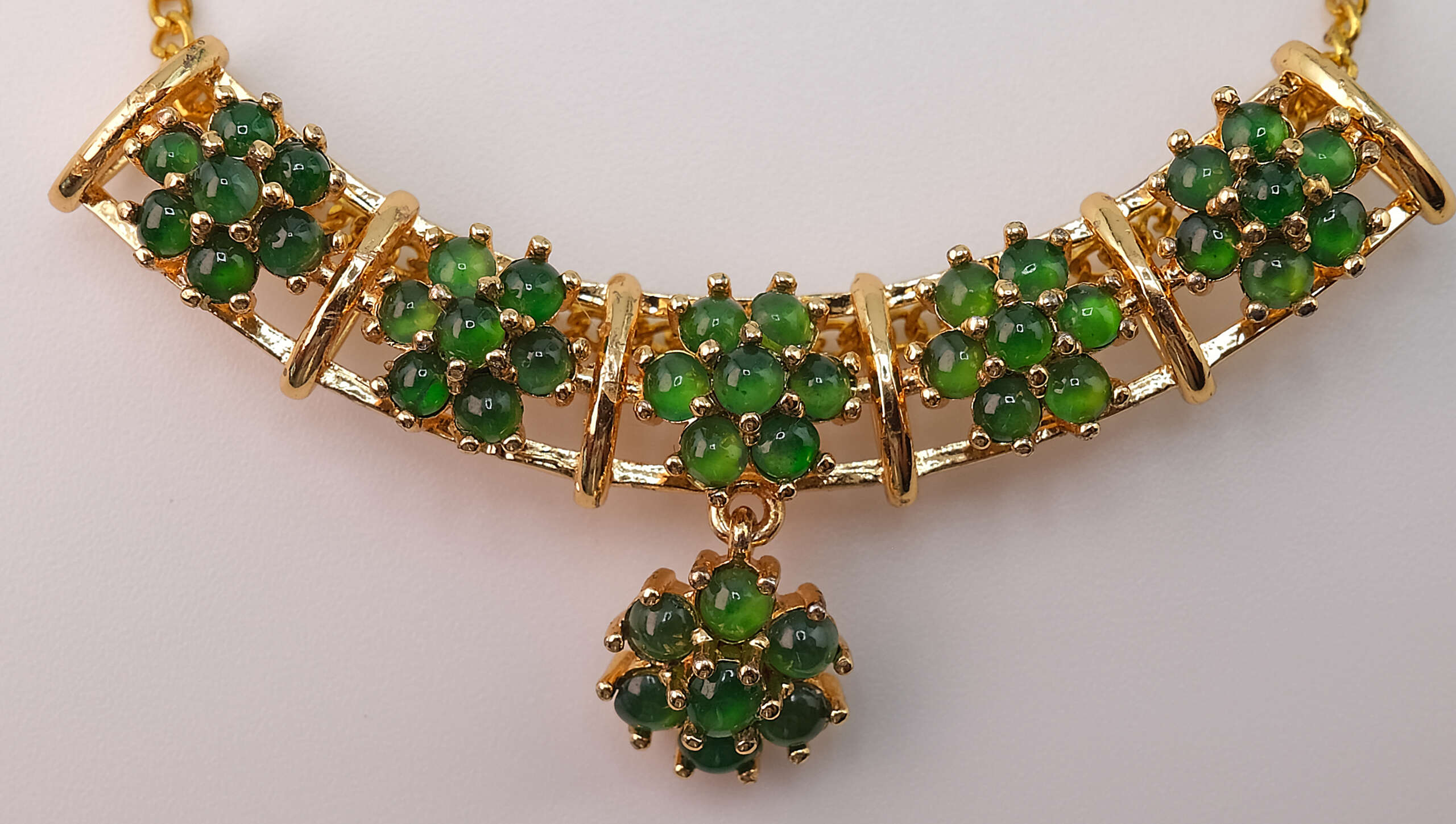 Detailed close-up of full central bar pendant of Burmese A-Type jadeite necklace, featuring five floral clusters of round green jadeite cabochons with one dangling drop cluster below