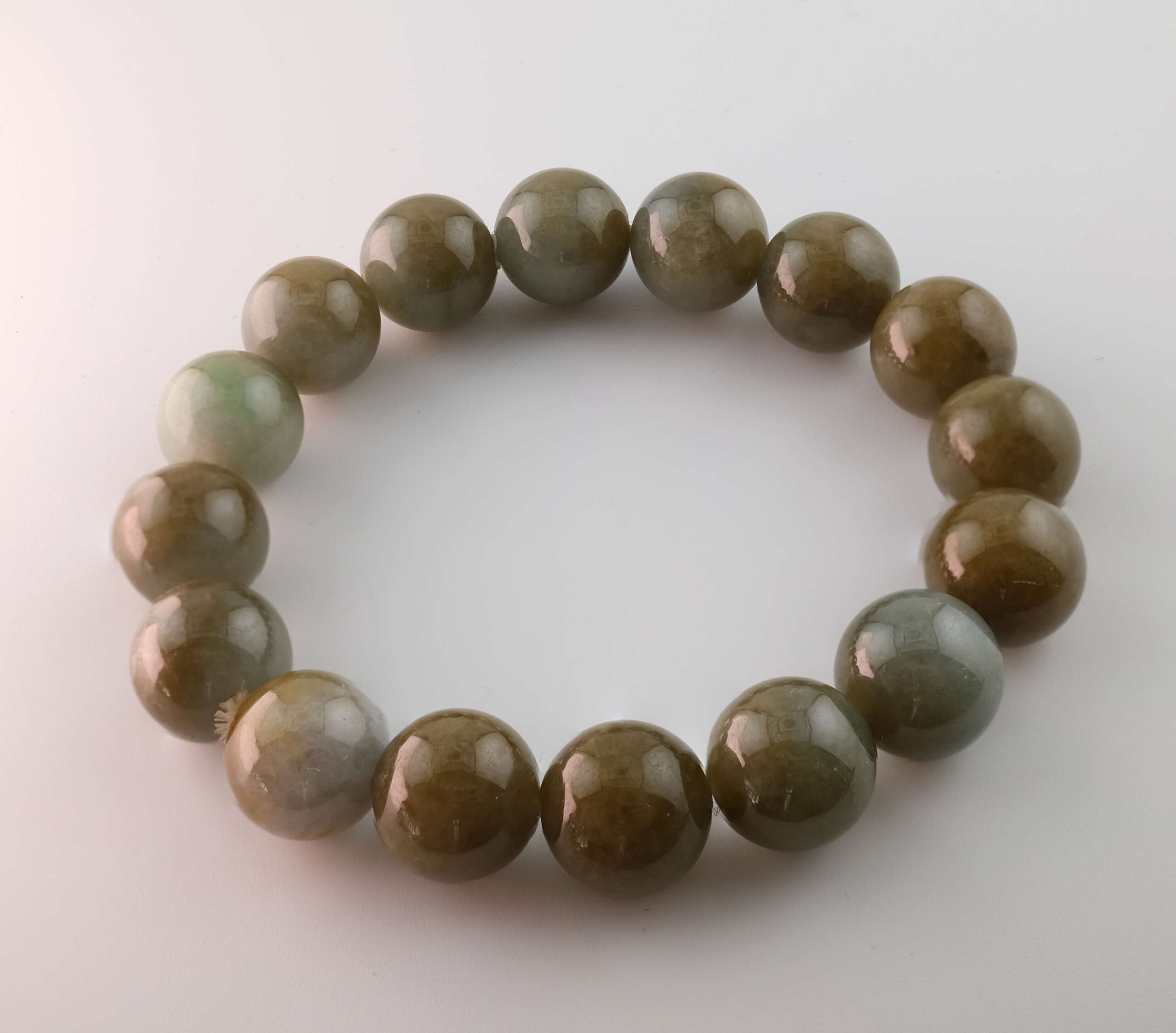 Top view of Burmese jadeite beaded bracelet featuring uniform 13.4 mm natural A-type jadeite beads with subtle gradient from grey-green to moss tones, fine polish, and natural sheen.
