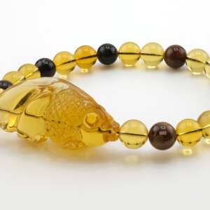 Side view of Cretaceous Burmese Burmite amber bracelet with carved fish centerpiece and uniform 8mm beads, highlighting polish, clarity, and natural golden coloration.