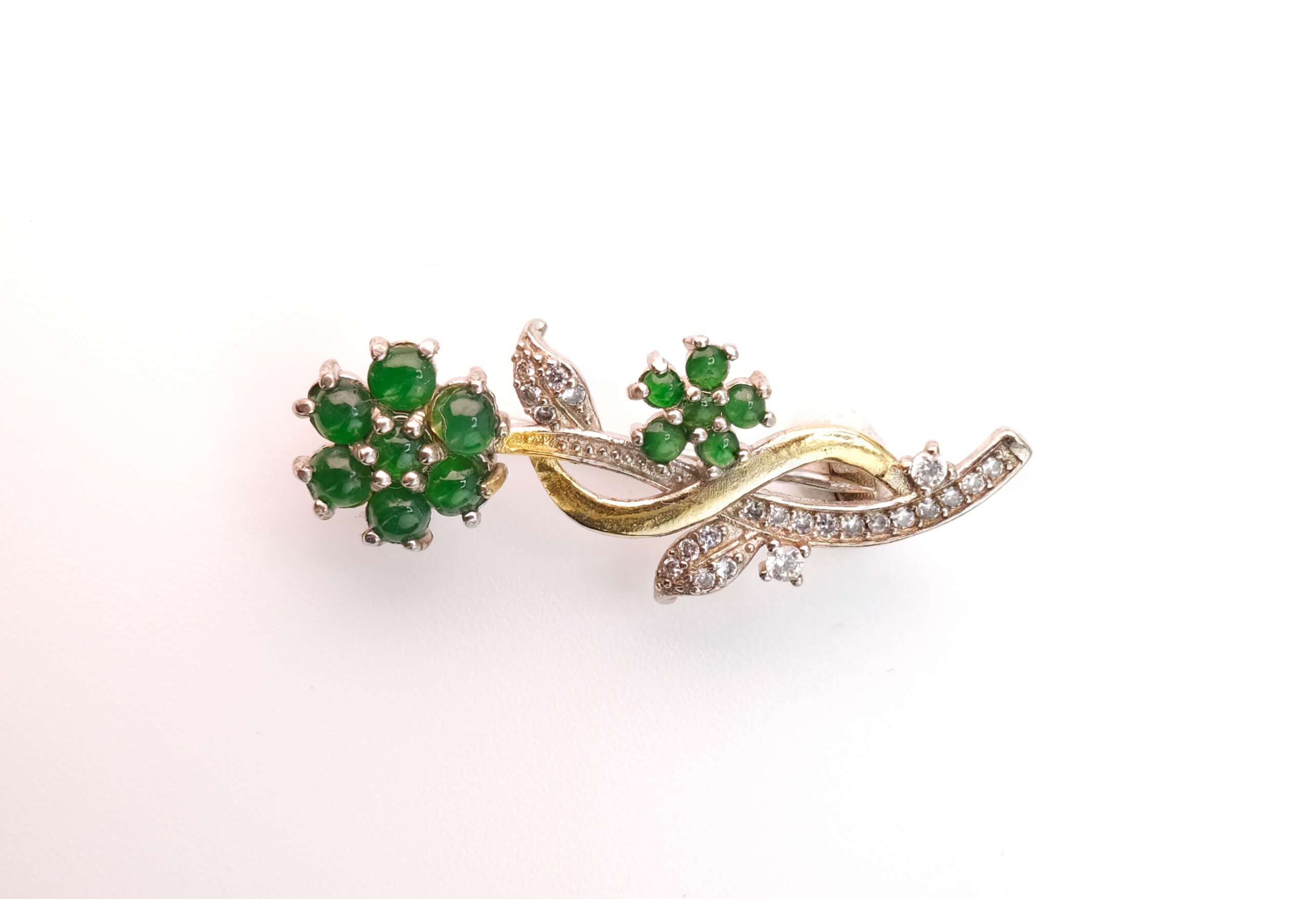 Natural Burmese jadeite floral brooch with vivid green cabochons and pavé diamond leaves in gold and silver alloy, photographed in studio lighting for GalaxyGems NYC — a refined piece symbolizing prosperity and timeless Myanmar artistry.
