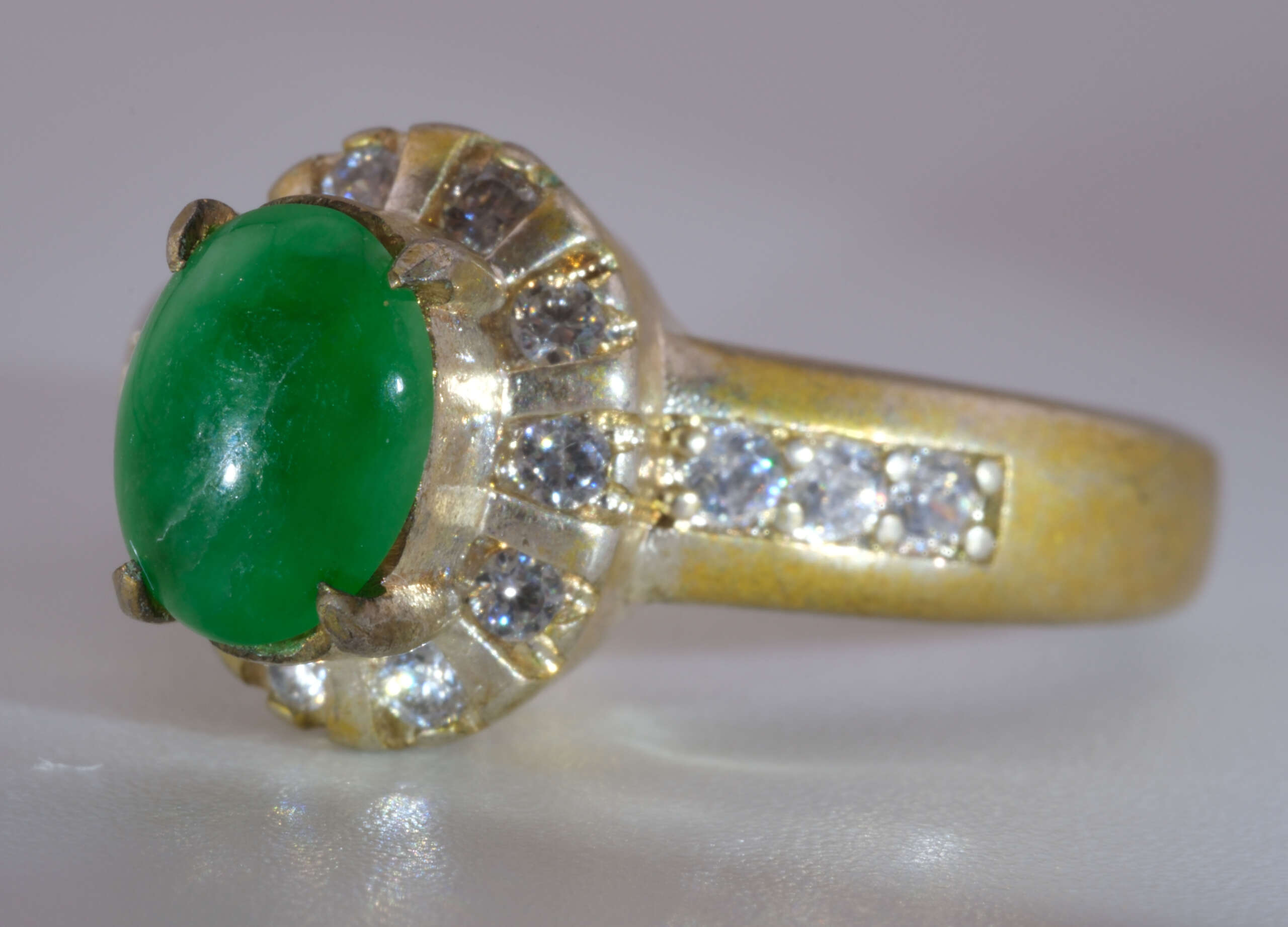 Close-up of vivid green Burmese jadeite jade oval cabochon ring with yellow-gold halo and accent stones, size 5