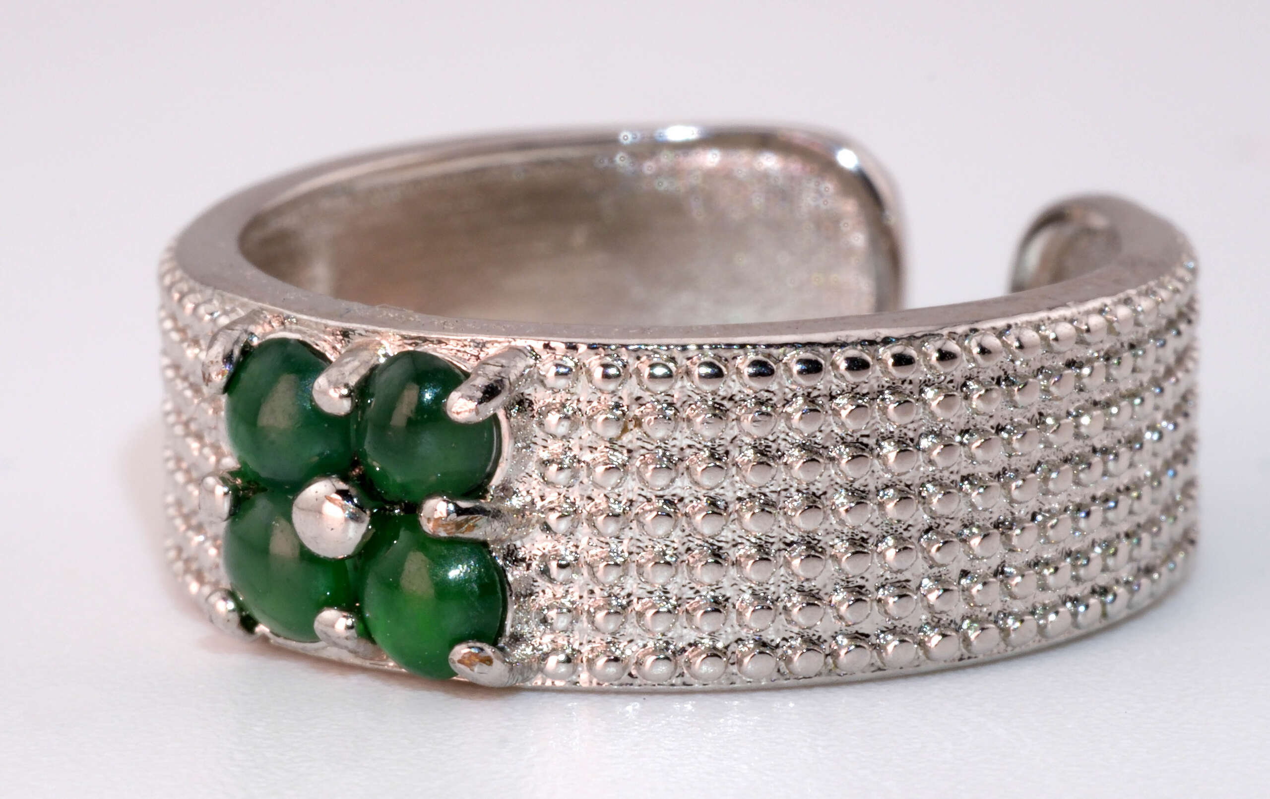 Side view of the men’s jadeite ring highlighting the raised gemstone cluster and silver bead-pattern band.