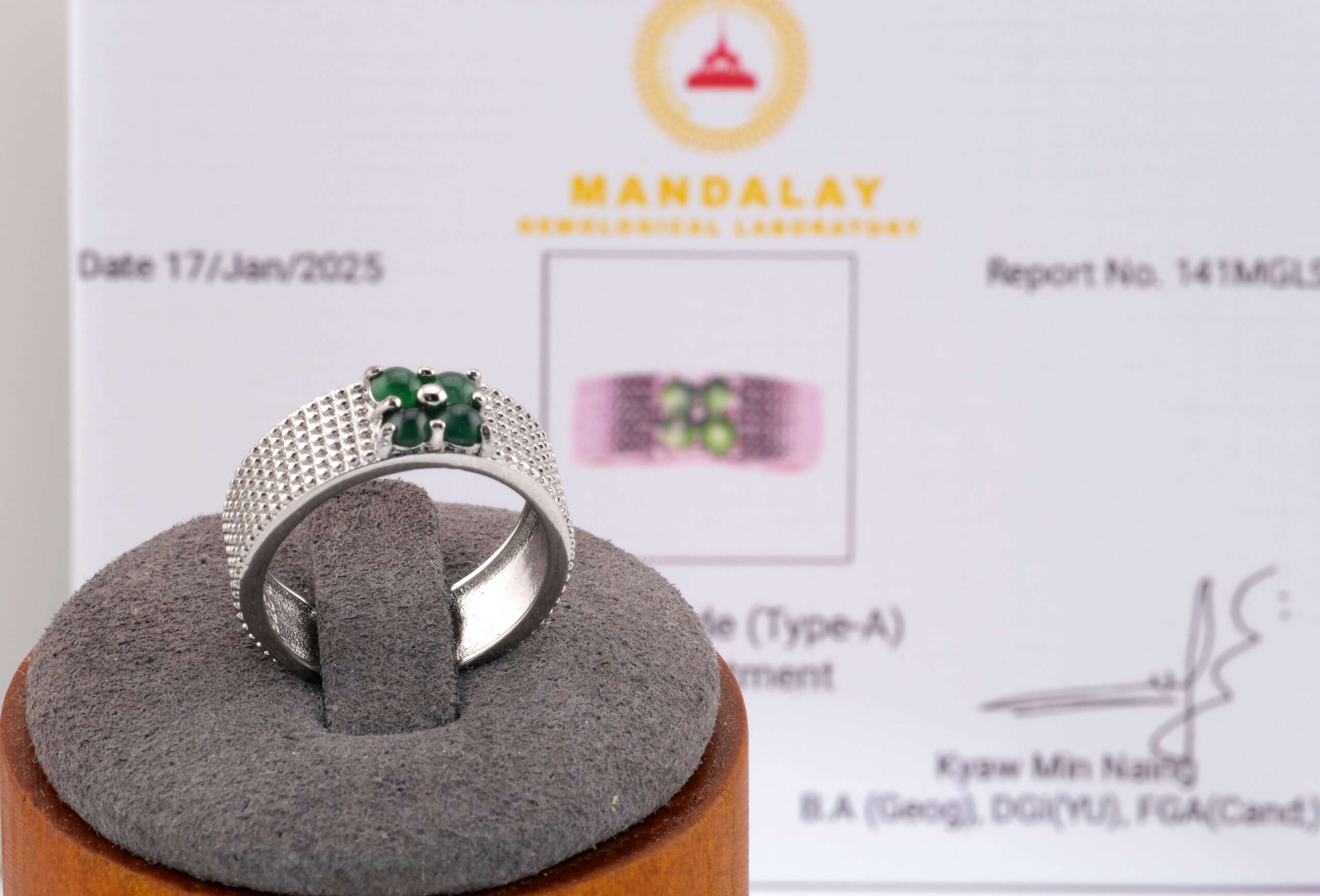 Men’s jadeite ring displayed on a stand in front of its Mandalay Gemological Laboratory certificate.