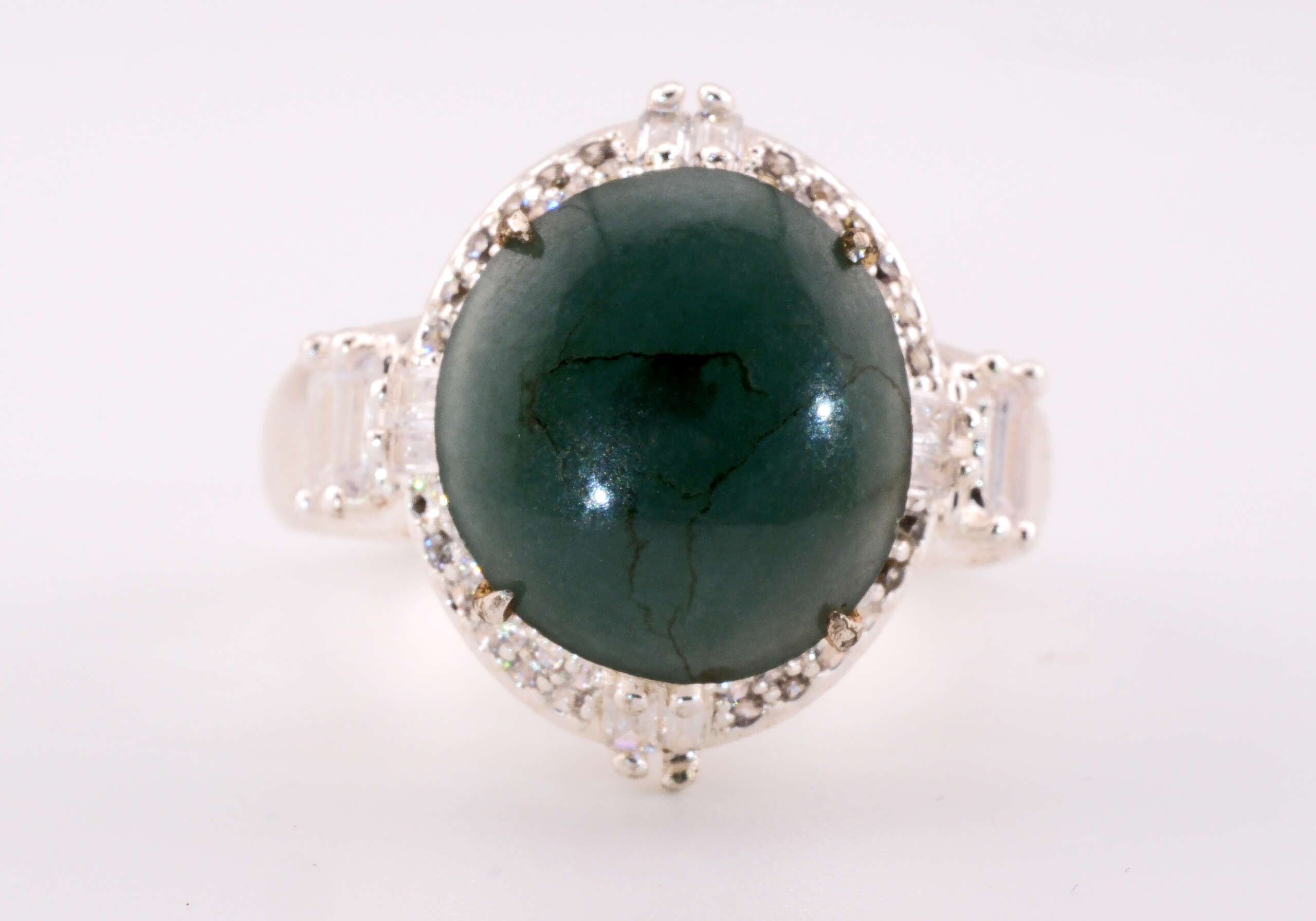 Front-facing view of the jadeite ring showing the large oval bluish-green cabochon and symmetric halo of small white accent stones