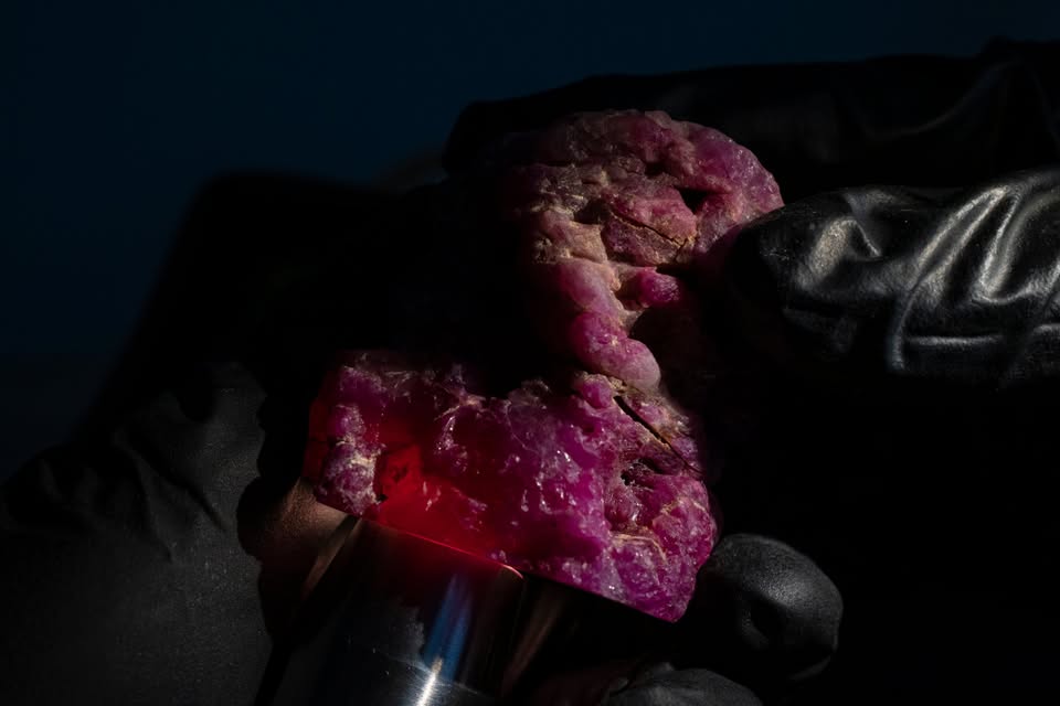 Rough mogok burmese natural ruby crystal with a gem torch illuminating the crystal body of the stone