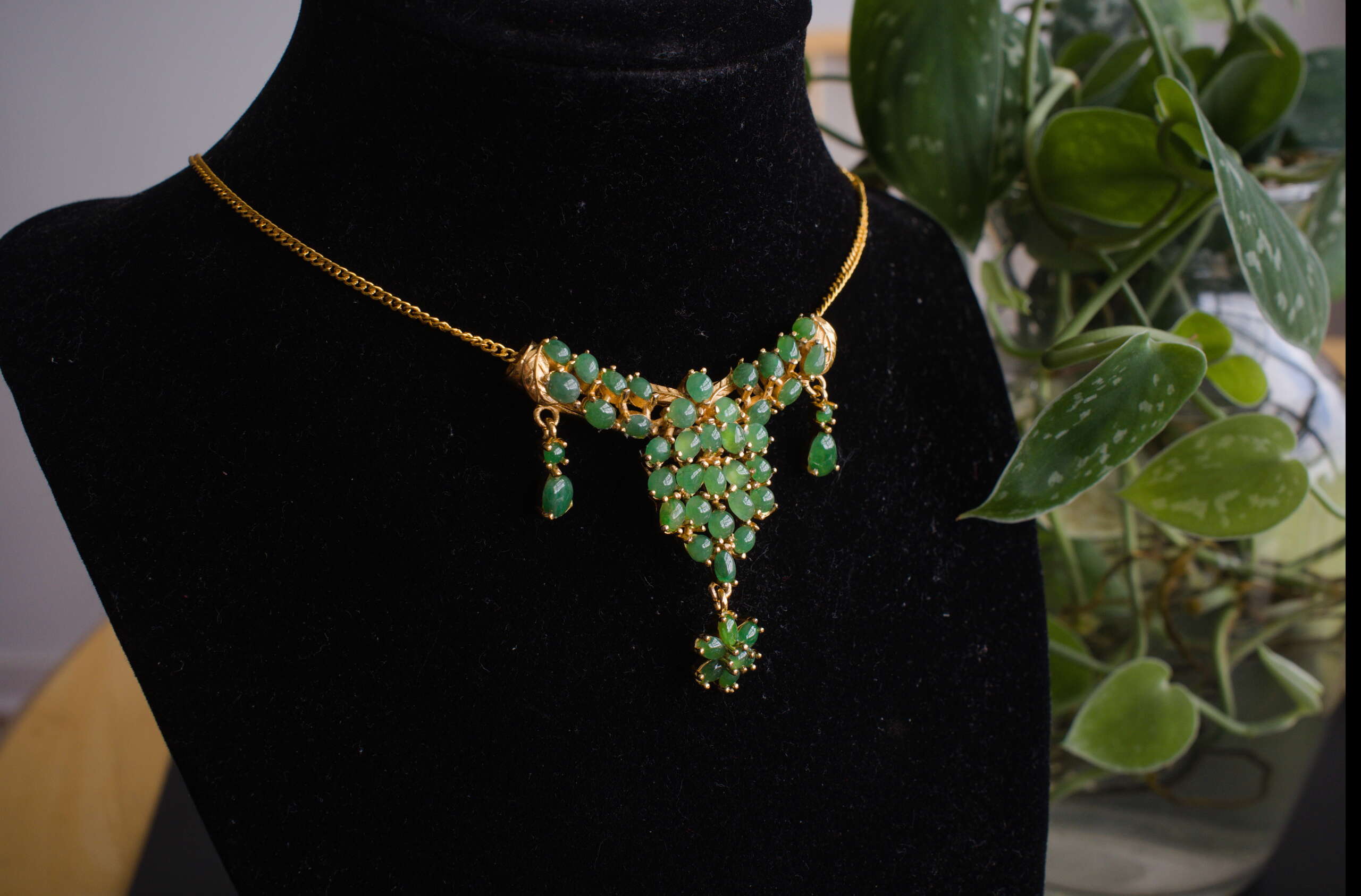 Myanmar jade cluster necklace shown on black display bust, 18-inch gold-tone chain with 2x2 inch pendant and floral drop.